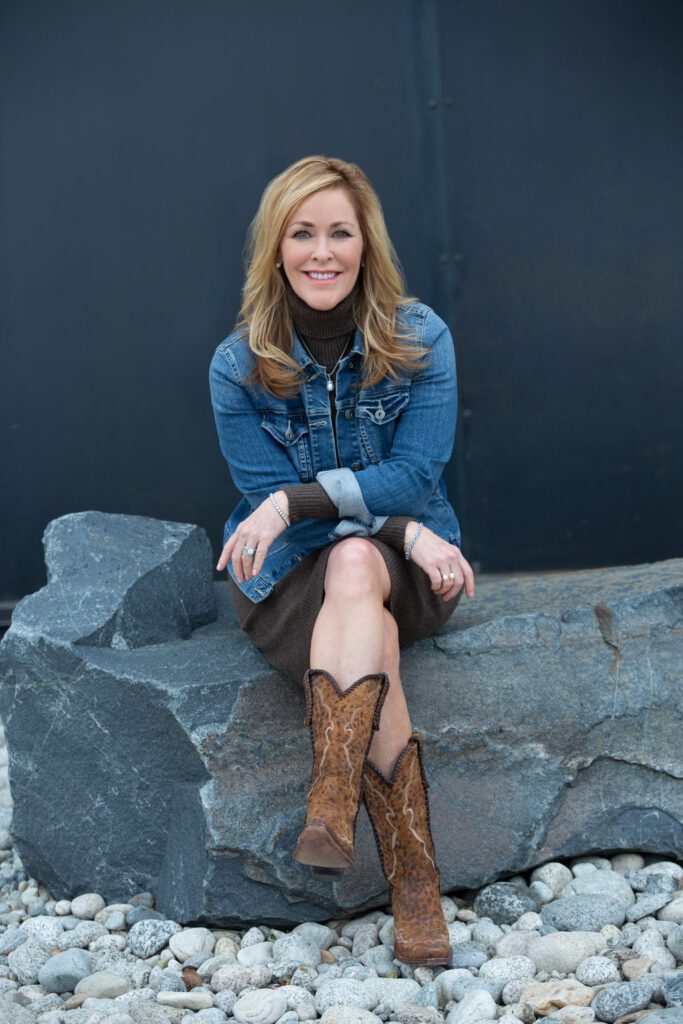 A professional image of Shannon Wagner sitting on a landscaping rock in front of a building